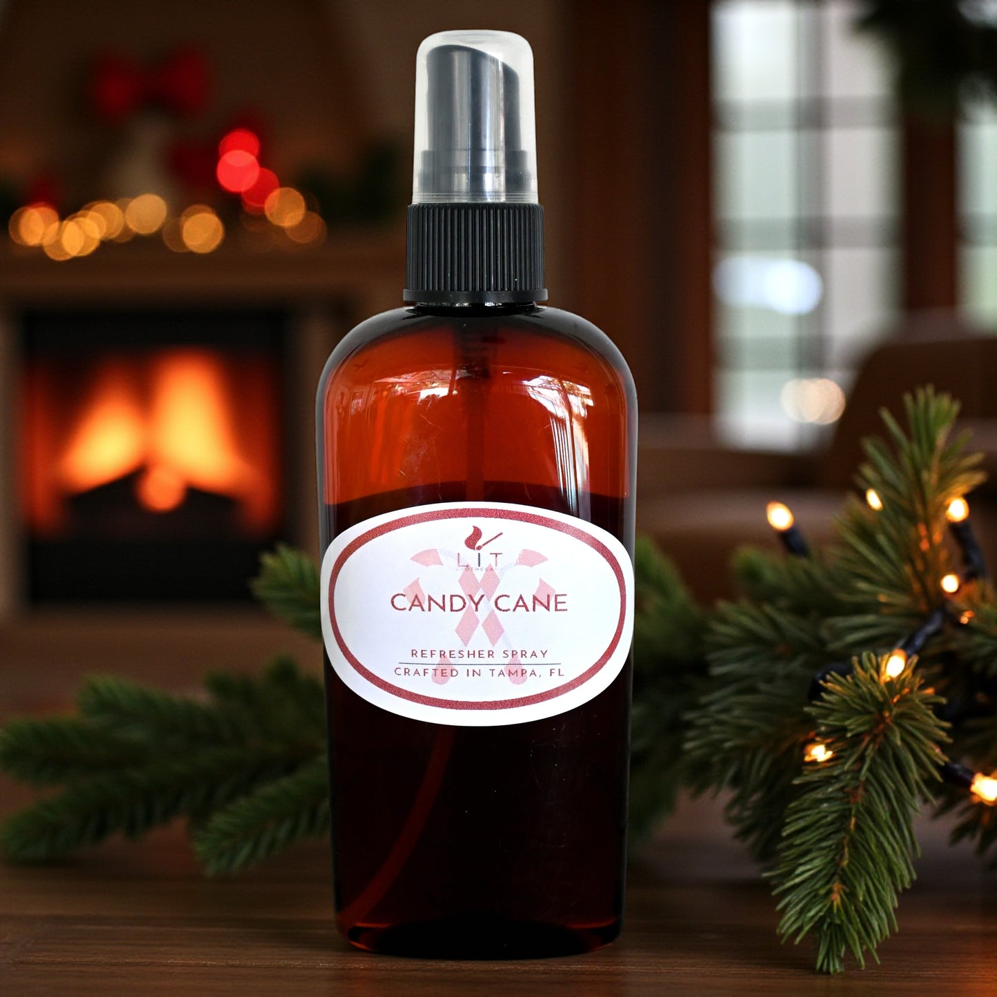 Candy Cane Room Spray showcased with pine branches and a cozy fireplace background, perfect for creating a festive atmosphere.
