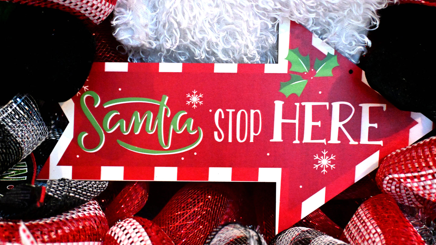 a red sign with santa's stop here written on it