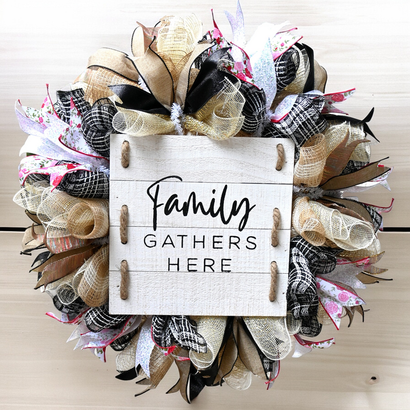Family Gathers Here wreath hanging on a front door with rose, gold, black, burlap and white ribbon accents for fall decor.
