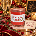 A festive holiday candle in a clear glass jar with a rose gold lid and a white label reading 'FA LA LA LATIO' in red text. The candle is styled on a marble surface with a 'Naughty List Approved' card, champagne flutes, red berries, green pine branches, and a blurred Christmas background.