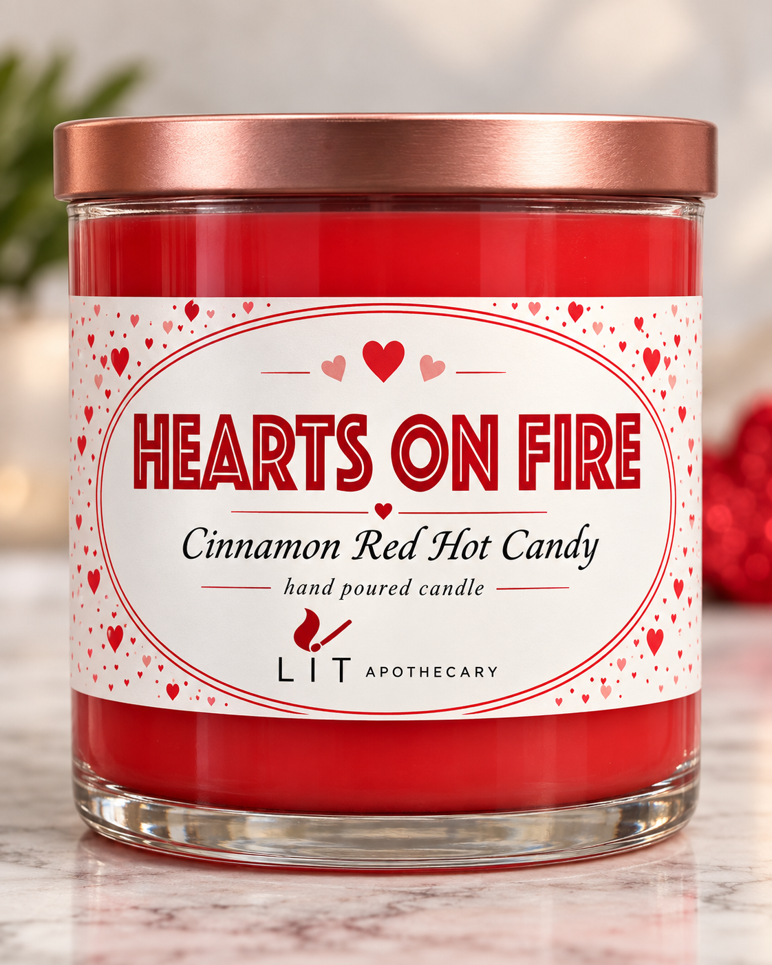 A glass jar candle with red wax and a metallic rose gold lid, featuring a white label with red hearts and the text 'HEARTS ON FIRE' and 'Cinnamon Red Hot Candy' by LIT APOTHECARY.