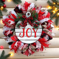 Joy Christmas wreath with white JOY ornament centerpiece, greenery, and red, black and white ribbon accents for front door decor.