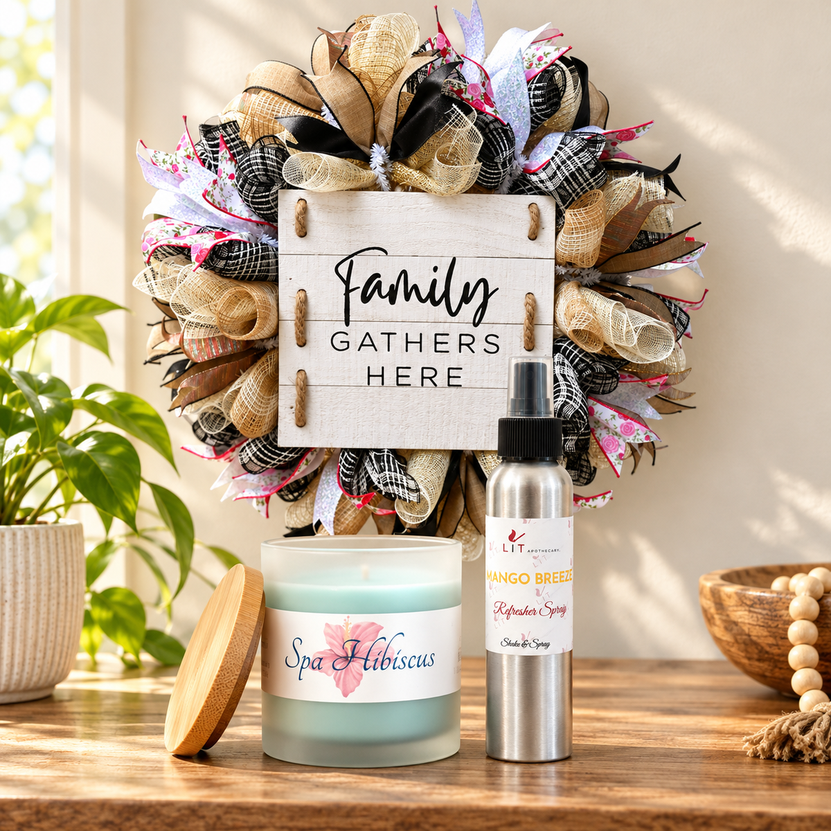 Family Gathers Here wreath above a wooden console with a Spa Hibiscus candle and Mango Breeze room spray from LIT Apothecary.