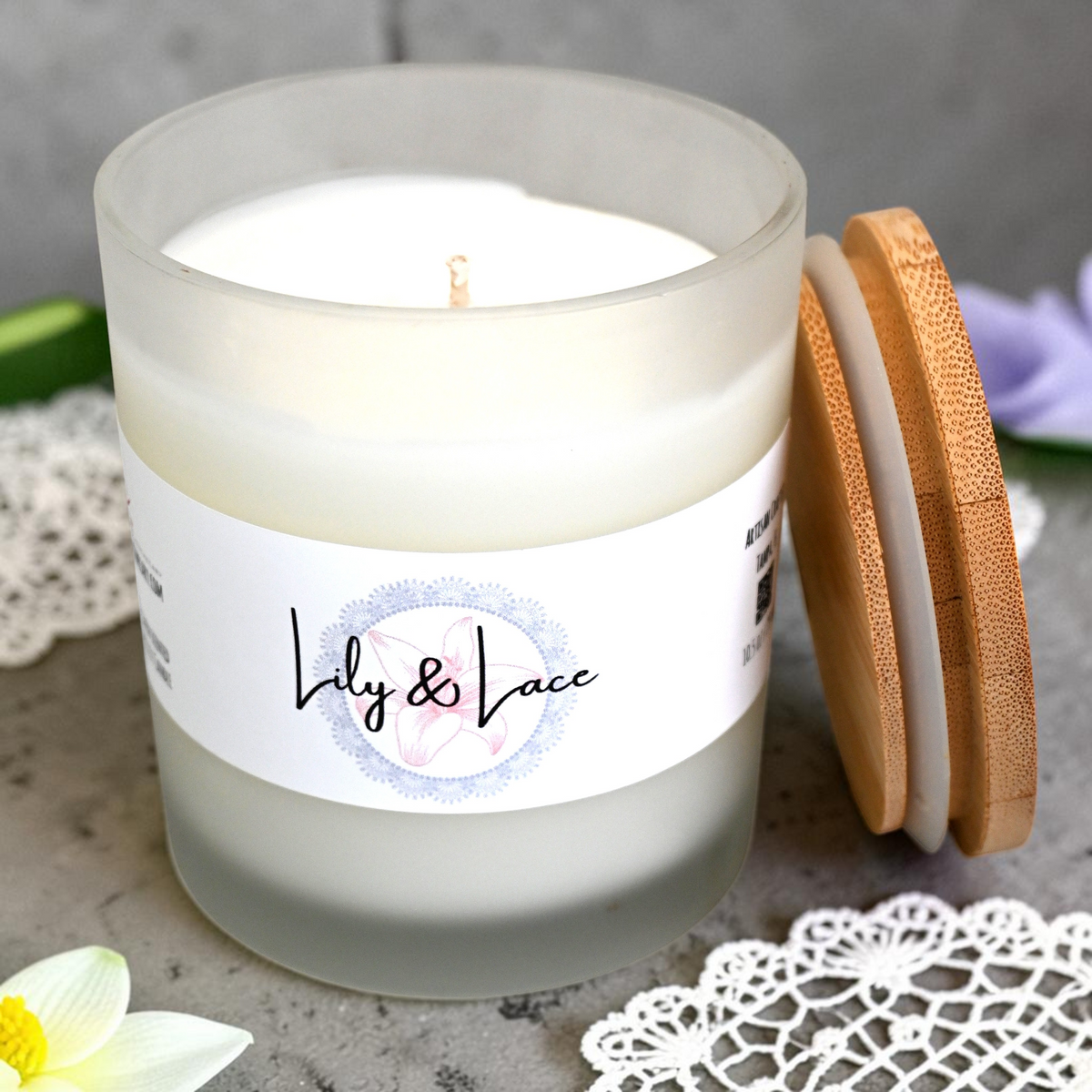 Top view of Lily & Lace candle in a frosted jar beside its bamboo lid and flowers