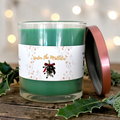 Open Under the Mistletoe candle showing green wax and a single wick, with its rose-gold lid resting beside the jar