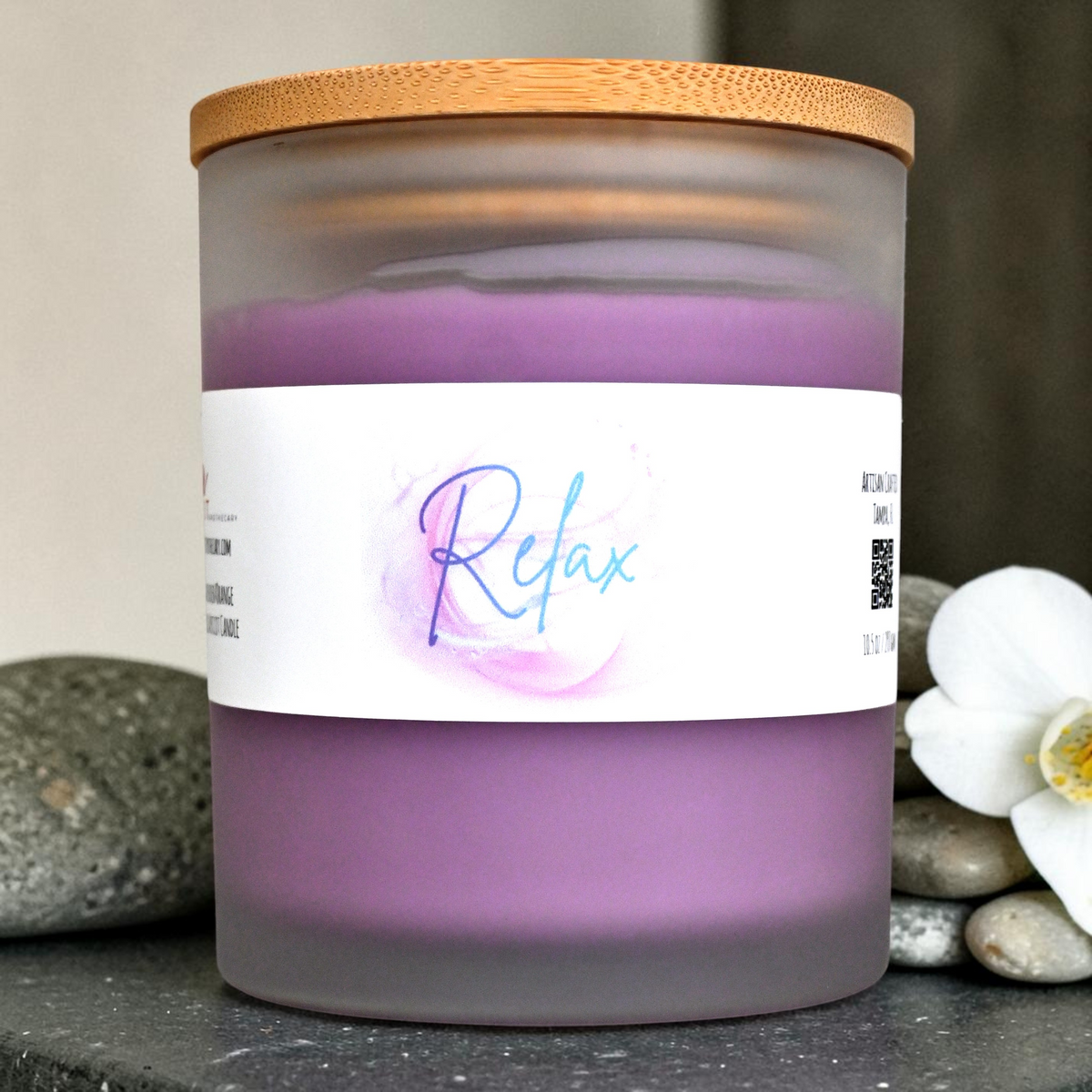 Relax candle with purple wax in frosted glass jar and bamboo lid on a stone spa setting
