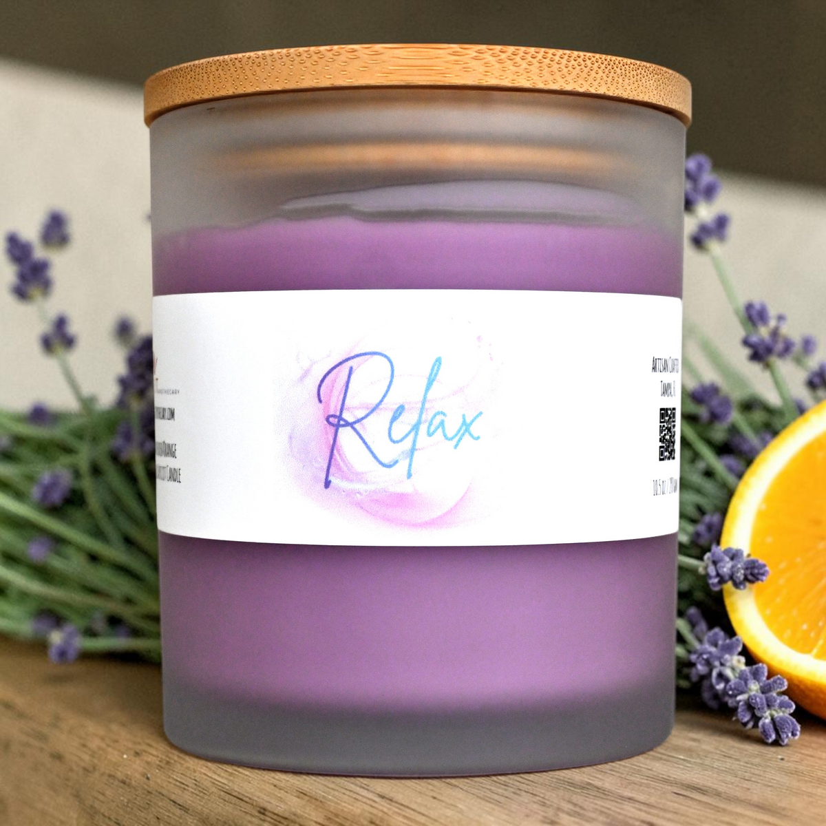 Relax lavender and orange candle in frosted glass jar with bamboo lid beside lavender and orange slice