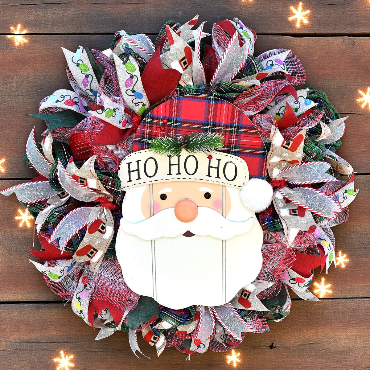 Santa Christmas wreath with cheerful Santa face, Ho Ho Ho plaid hat, and layered red, green and white holiday ribbons.