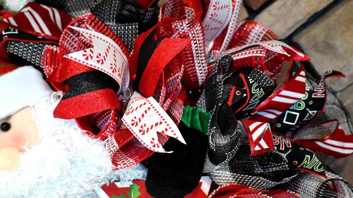 Close-up of Santa Christmas wreath ribbons with Santa belt, Naughty or Nice, peppermint and candy cane patterns.