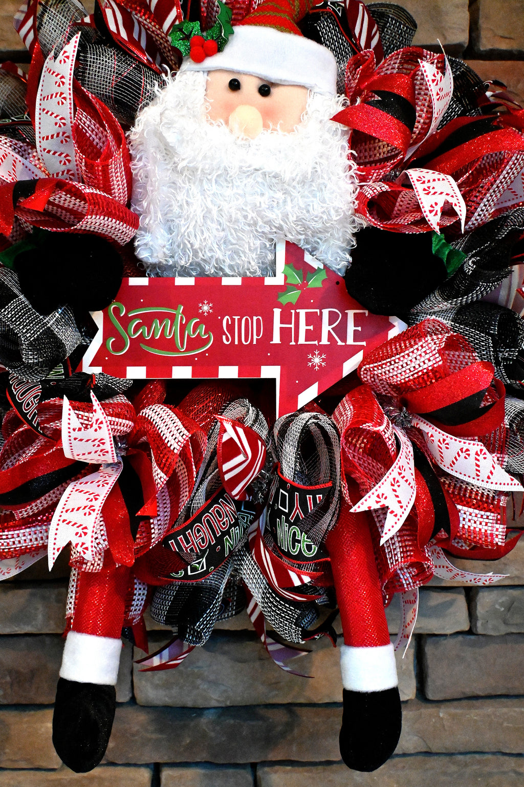 Close-up of Santa figure on the Santa Stop Here Christmas wreath with playful holiday front door decor.