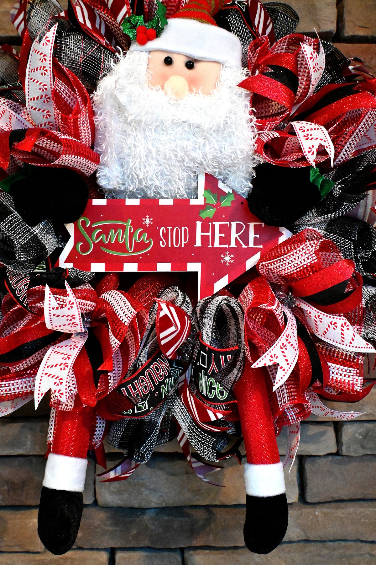 Close-up of Santa figure on the Santa Stop Here Christmas wreath with playful holiday front door decor.