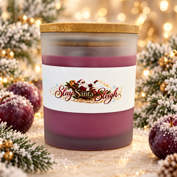 Slay Santa Sleigh Frosted Sugar Plum candle in plum-colored frosted glass with bamboo lid, styled with frosted plums and Christmas greenery.