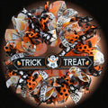 Trick or Treat Halloween wreath with playful ghost sign, orange, black, yellow and white ribbons, and festive front door decor.