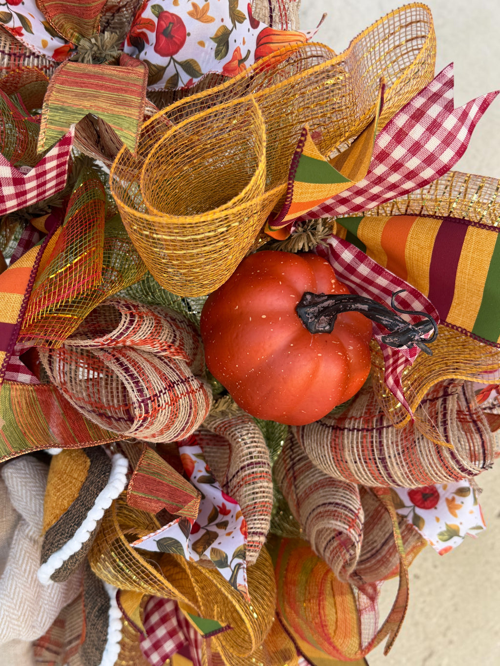 Orange pumpkin accent surrounded by gold deco mesh, burgundy gingham, and fall striped ribbons on the turkey wreath