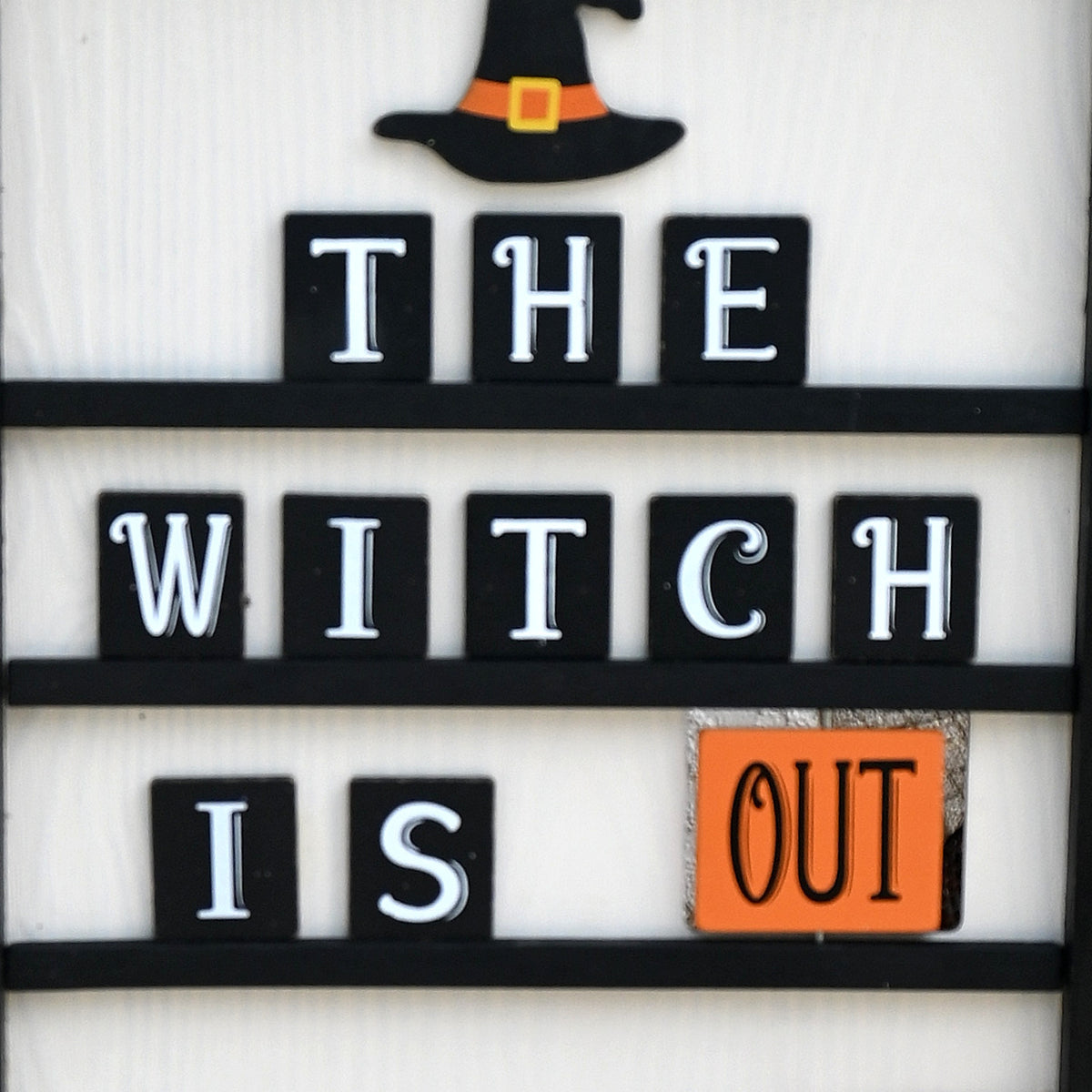 Witch Is Out side of reversible Halloween wreath sign with orange, black and white decor.