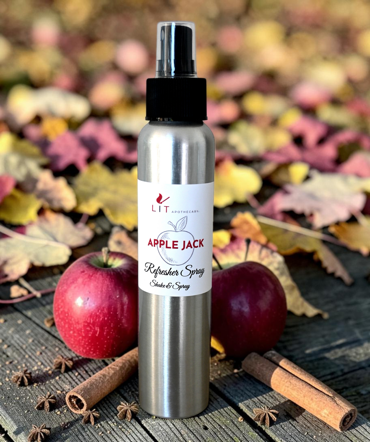 Lit Apothecary Apple Jack room spray with red apples, cinnamon sticks and colorful fall leaves