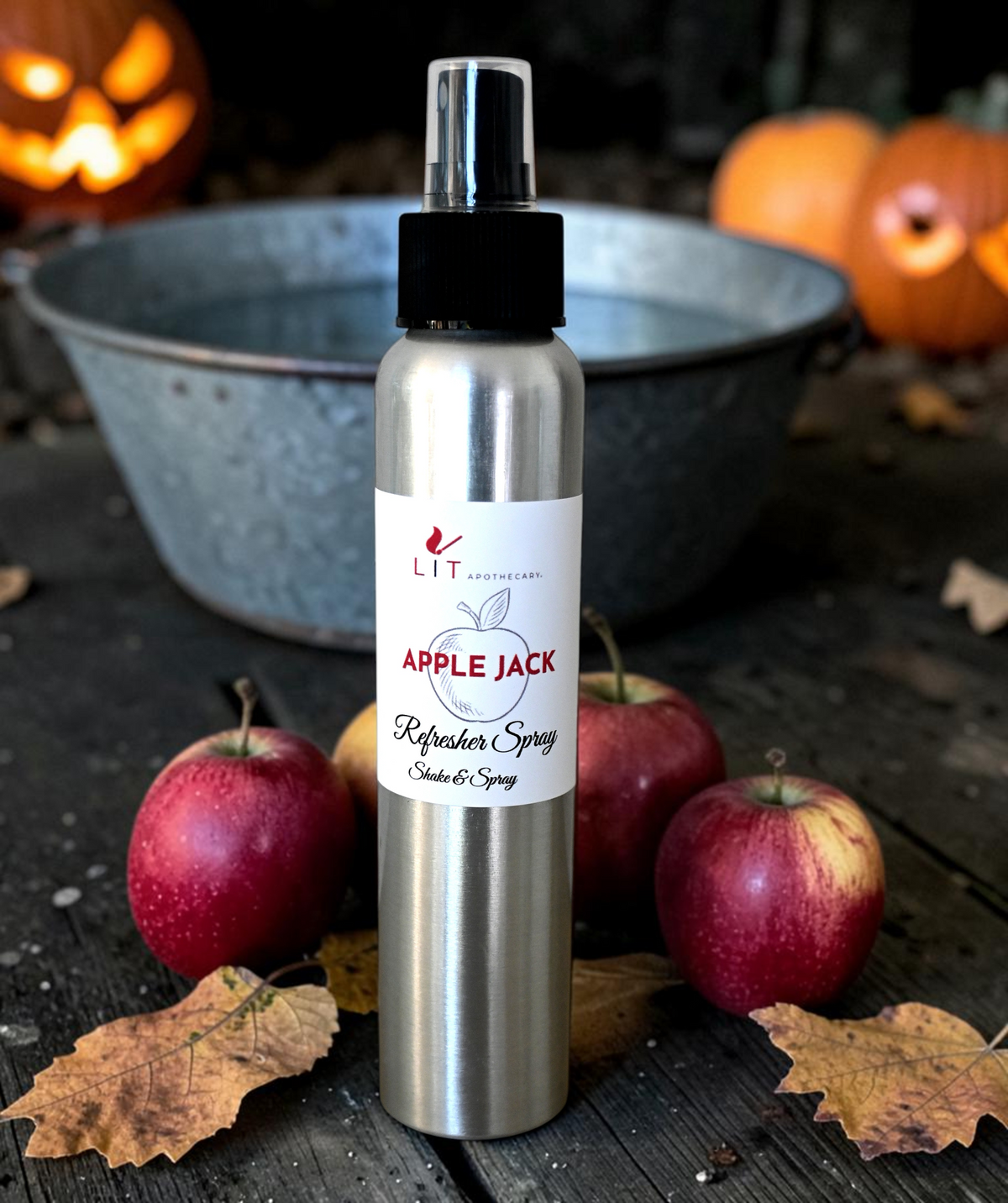 Lit Apothecary Apple Jack room spray with red apples, autumn leaves and glowing Halloween pumpkins