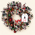 Deck the Halls Christmas wreath with patterned ribbons, a white holly sign, and jingle bells on a brown leather strap