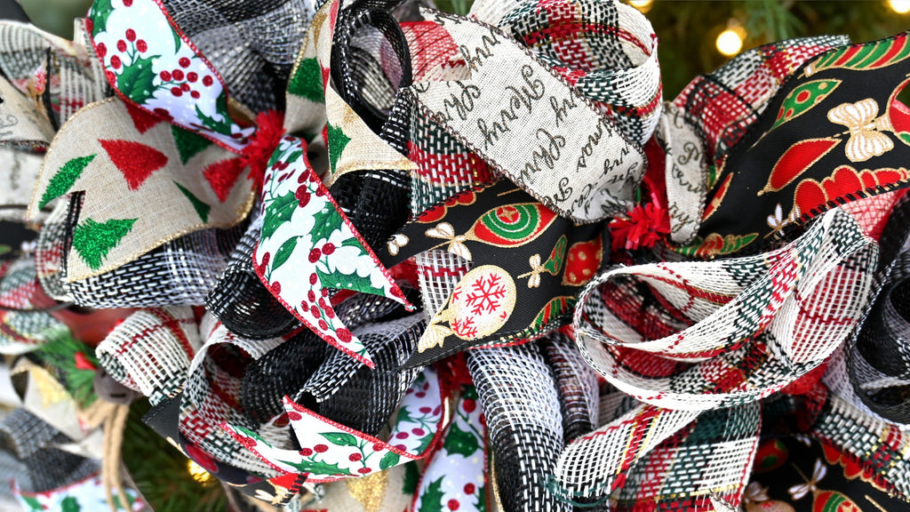 Close-up of holly berry, glittered Christmas tree, ornament, and Merry Christmas ribbons with plaid and black mesh