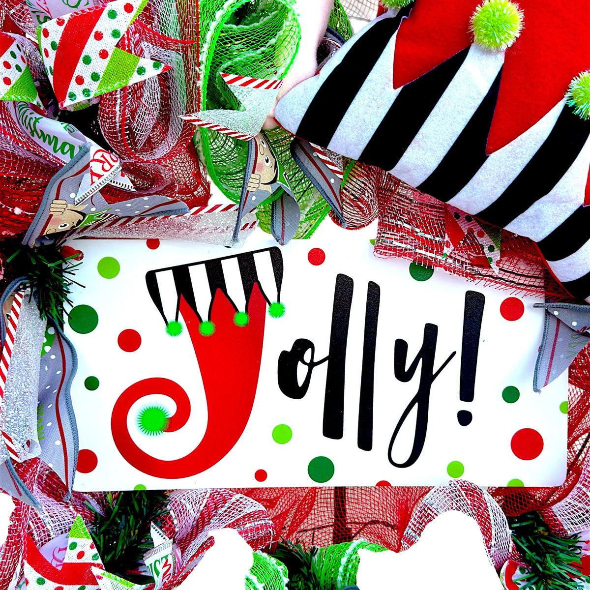 Jolly sign with red and green polka dots at the center of the Christmas elf wreath.