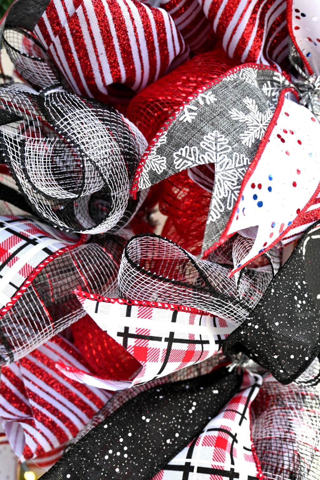 Close-up of plaid, snowflake and red striped ribbons with red and black-and-white mesh on snowman wreath