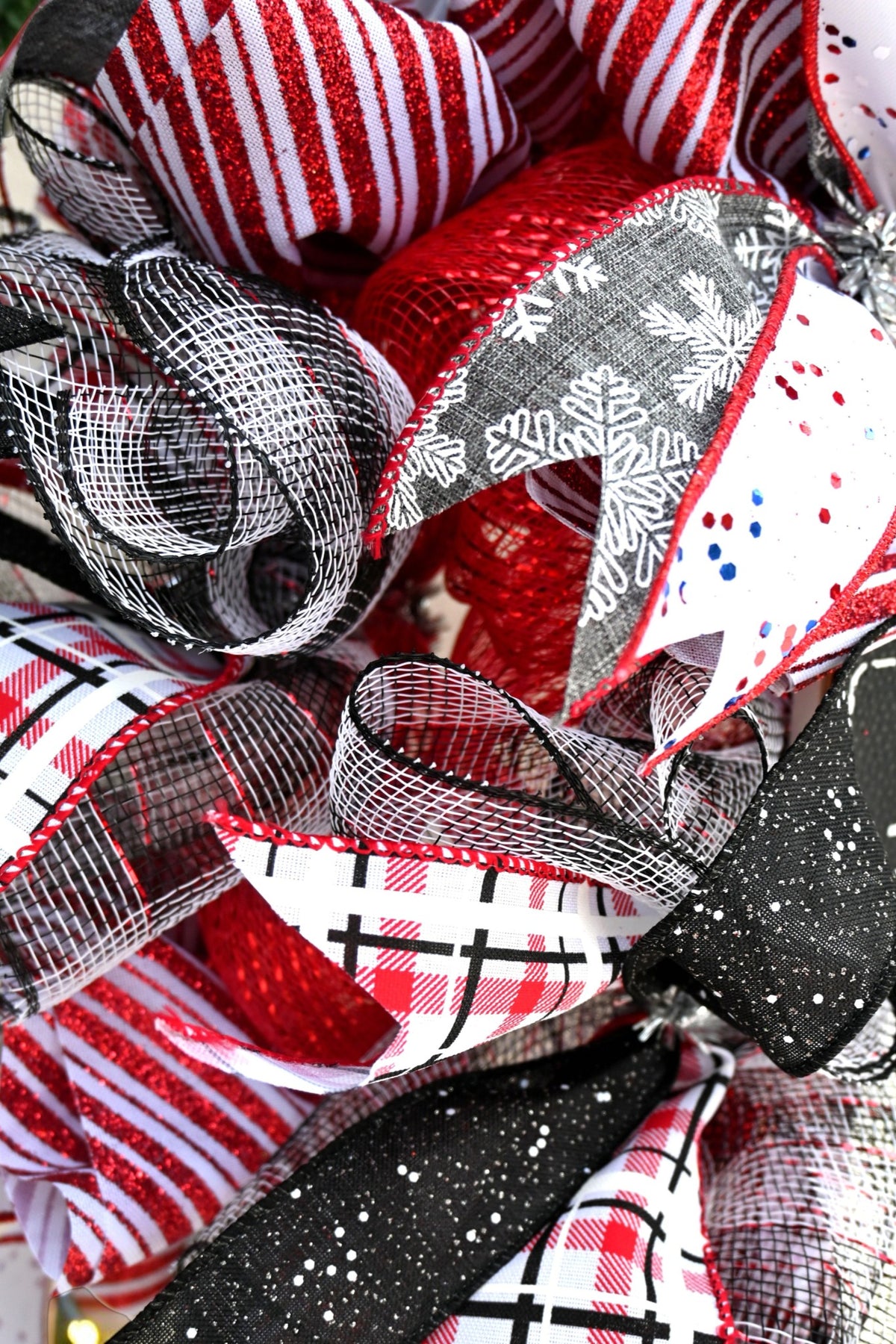 Close-up of plaid, snowflake and red striped ribbons with red and black-and-white mesh on snowman wreath