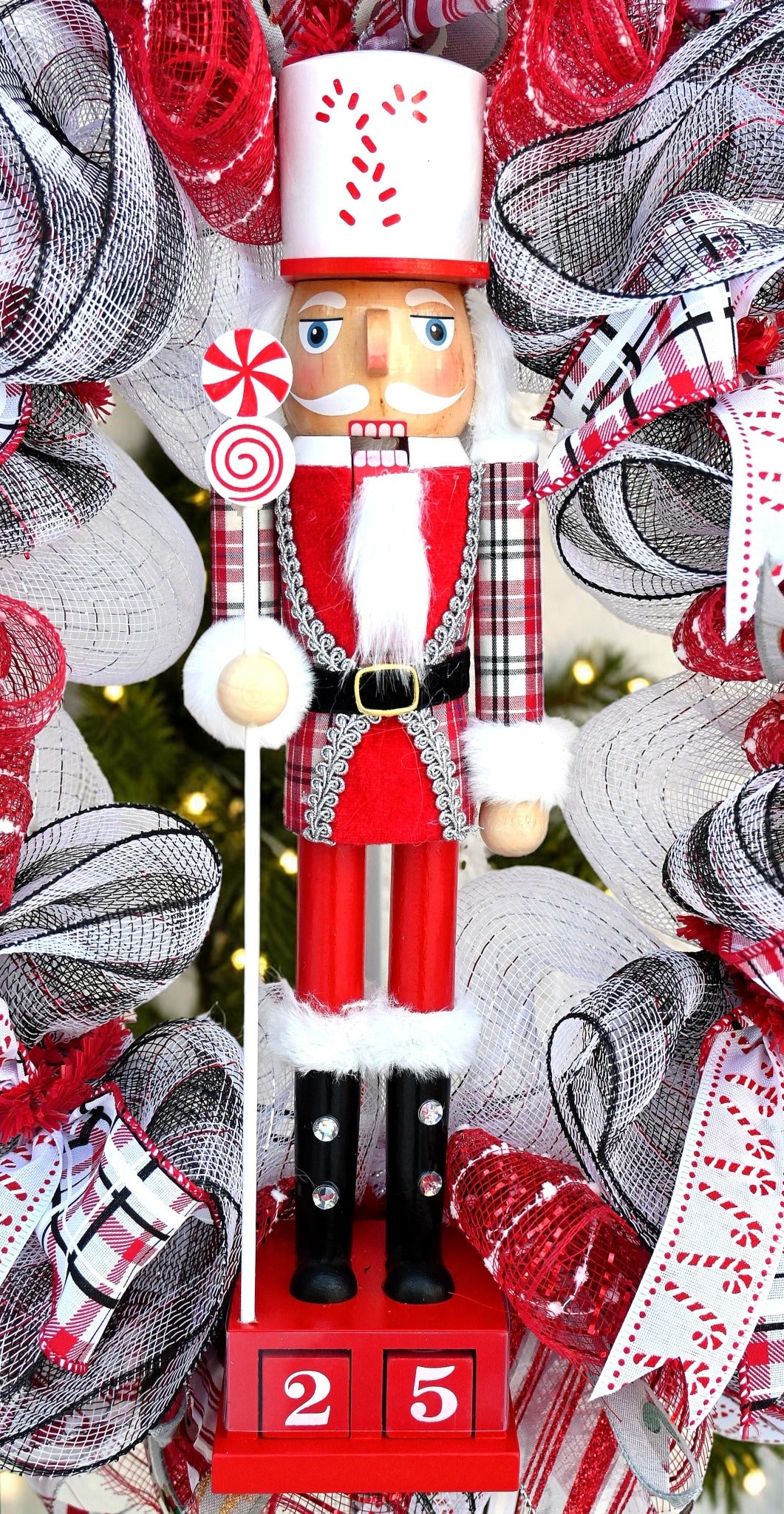 Red nutcracker centerpiece with a white candy cane hat, peppermint staff, plaid sleeves, black boots and Christmas countdown blocks.