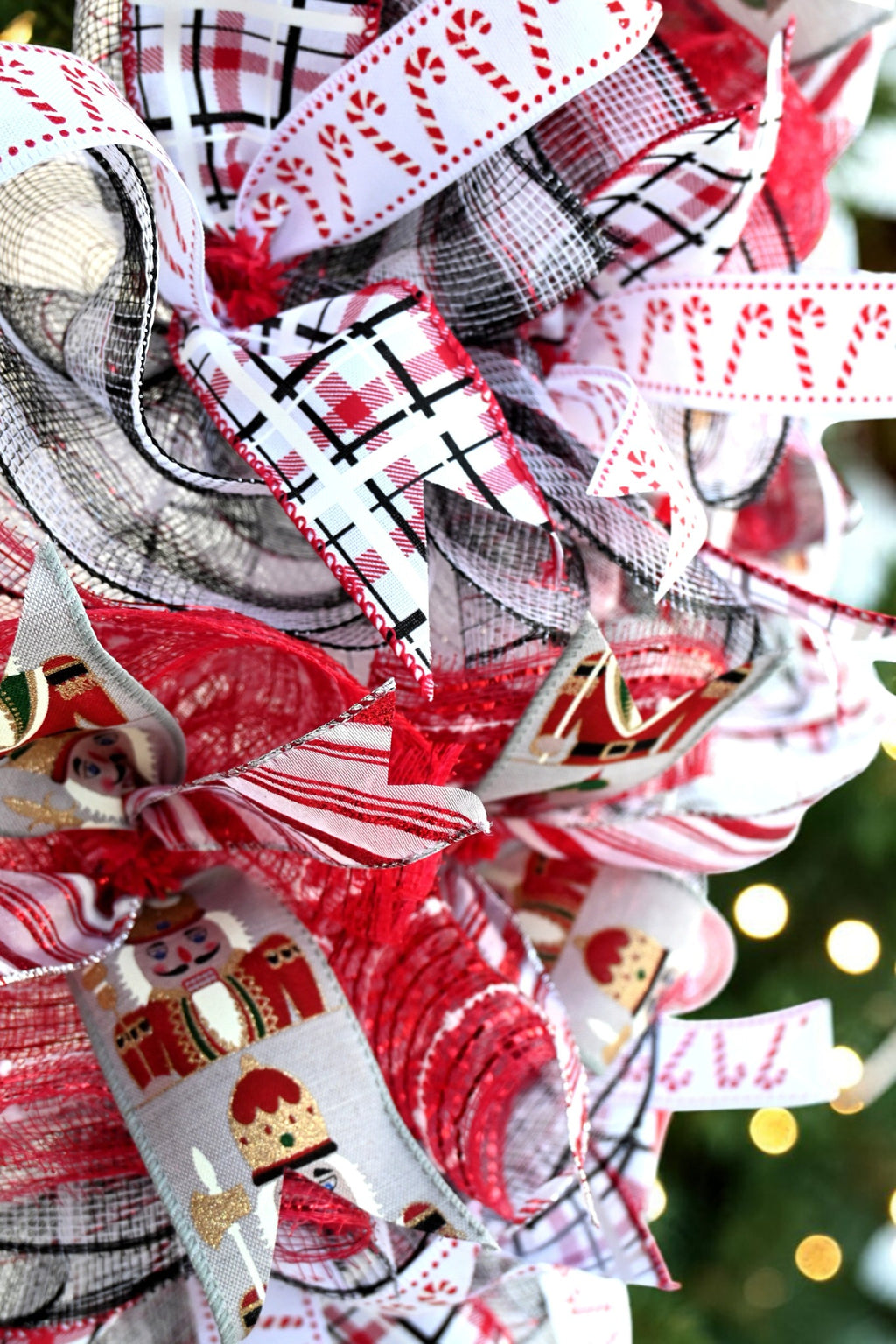 Close-up of candy cane, red and black plaid, striped and nutcracker-print ribbons with red, white and black mesh.