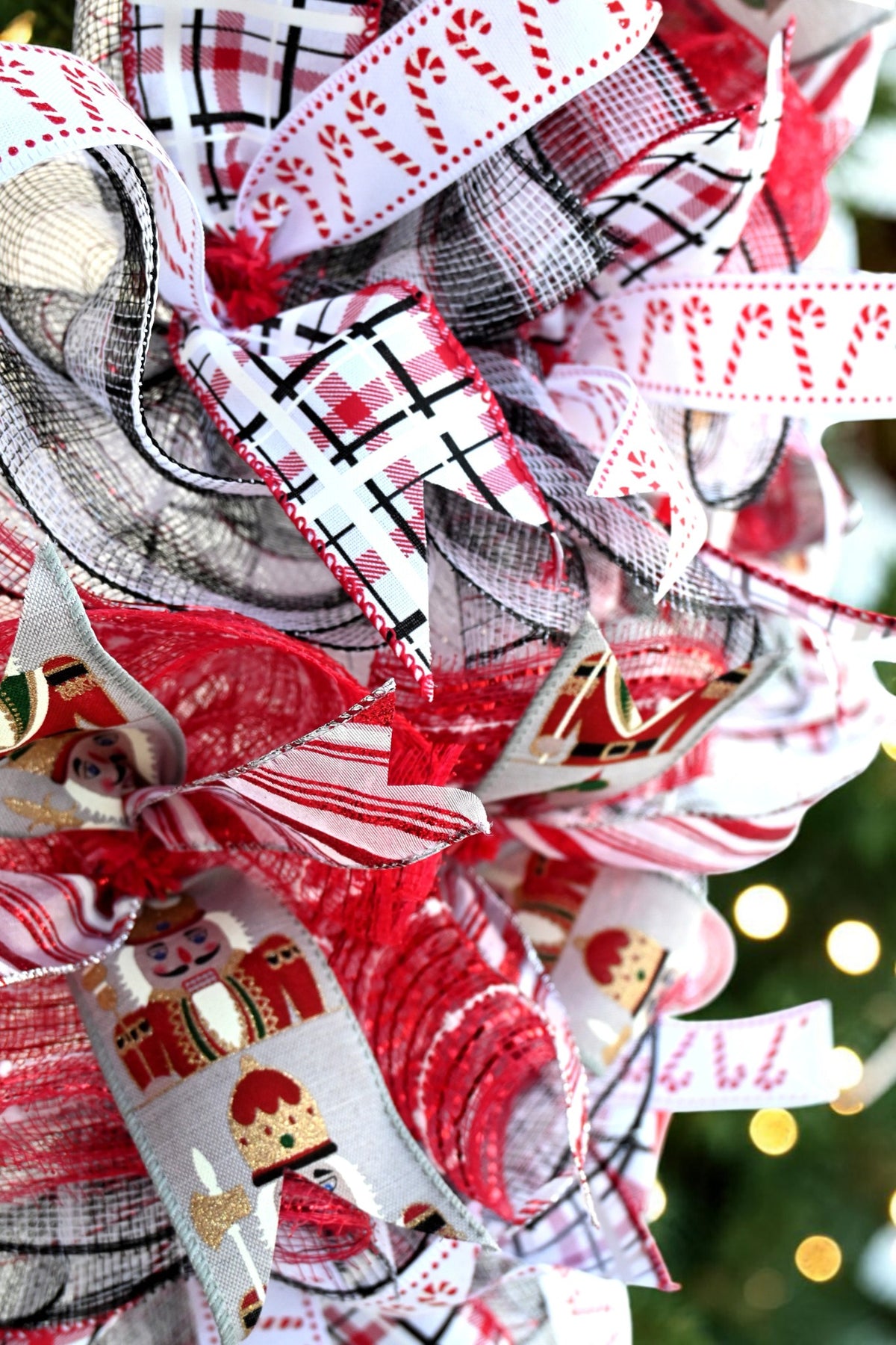 Close-up of candy cane, red and black plaid, striped and nutcracker-print ribbons with red, white and black mesh.