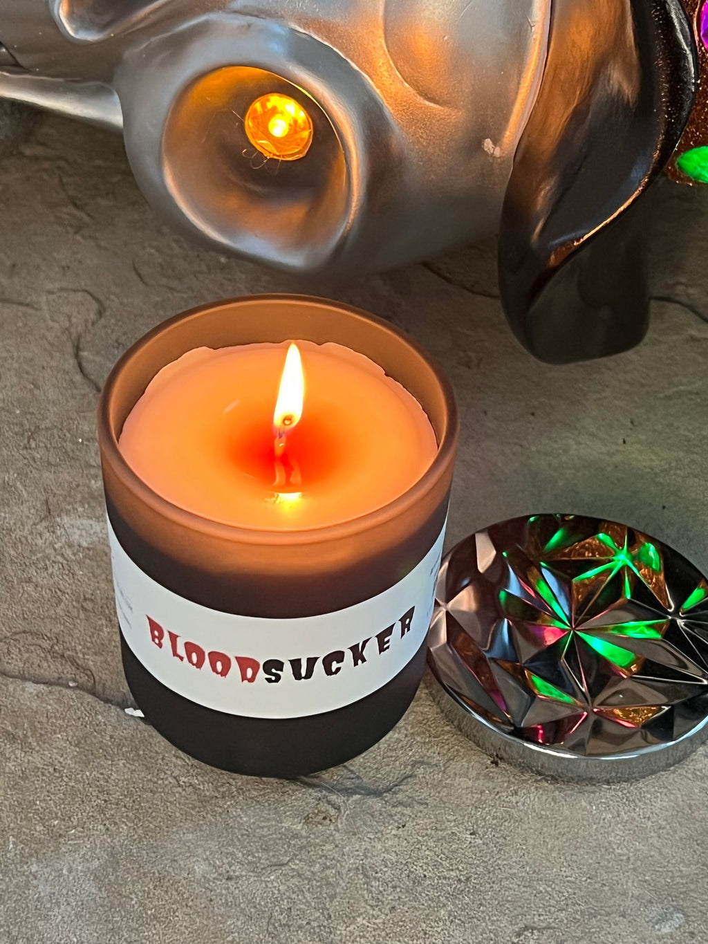 Angled close-up of Bloodsucker candle burning, showing a red wax pool around the wick