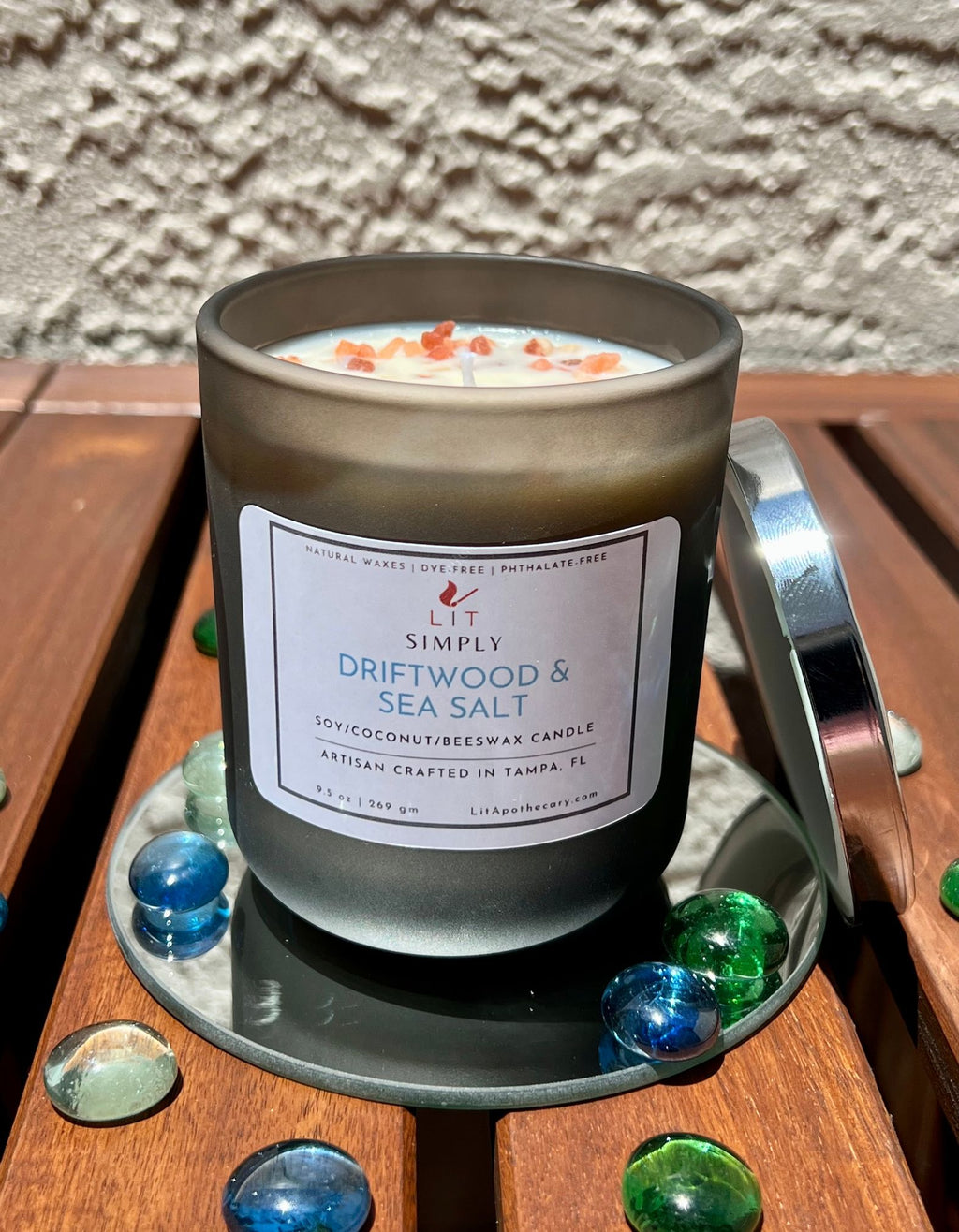 Open Driftwood & Sea Salt candle in previous black frosted jar with silver lid and pink salt crystals