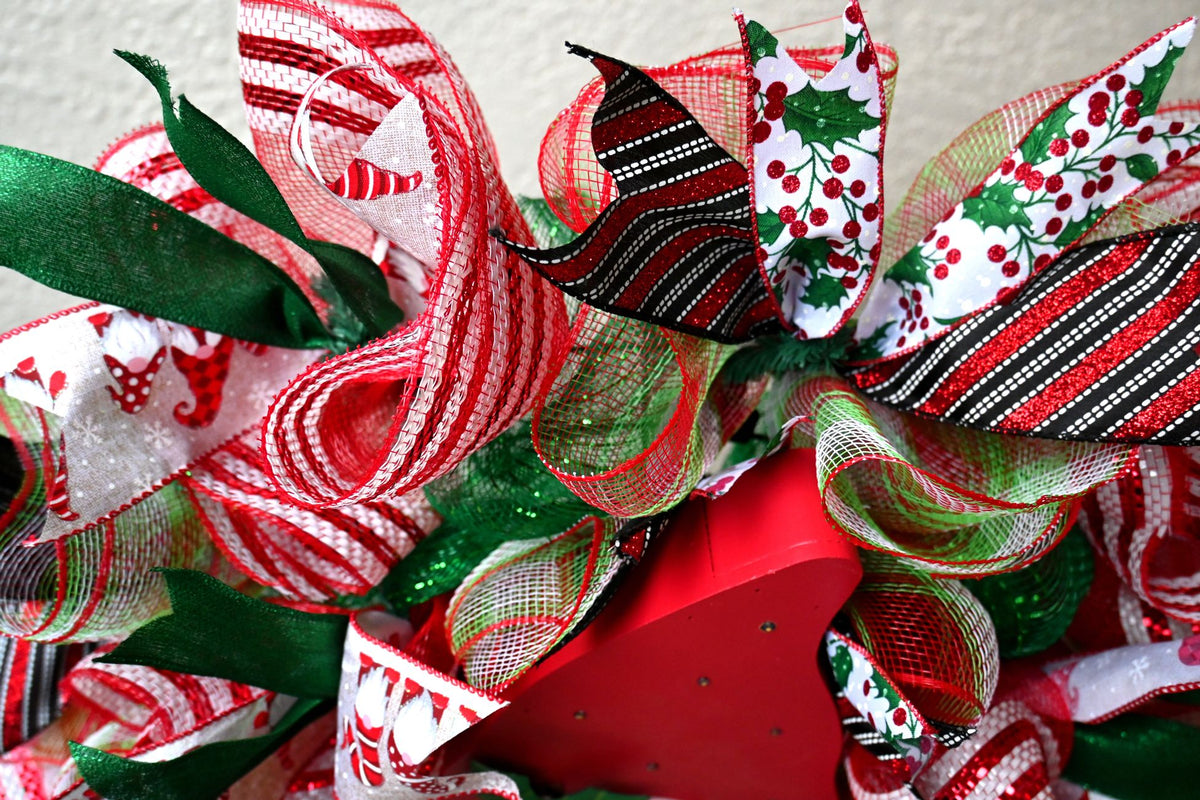 Close-up of striped, holly, gnome and emerald glitter ribbons on the Christmas wreath
