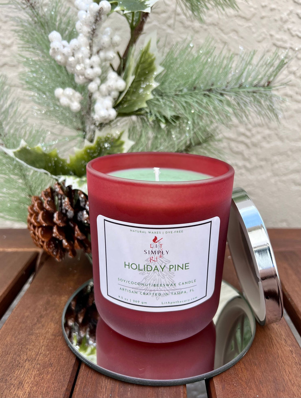 Open Holiday Pine candle showing pale green wax and a single wick, with silver lid beside the jar on a mirrored tray