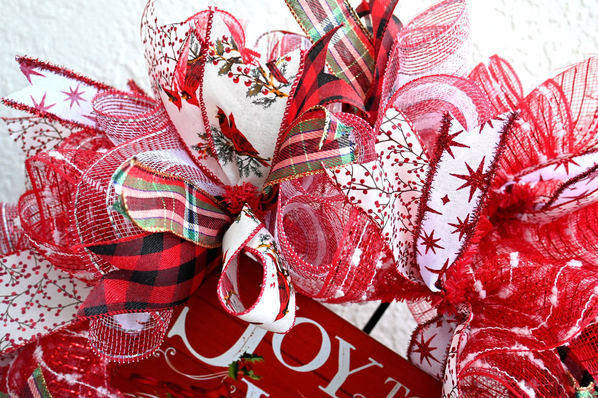 Close-up of Joy to the World Christmas wreath ribbons featuring cardinal, buffalo check, plaid, red, white, green, and black accents.
