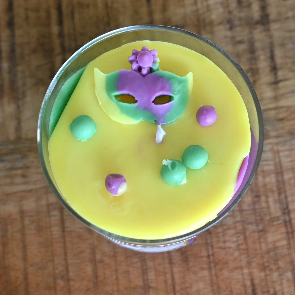 Top view of King Cake Candle with a Mardi Gras mask and festive beads