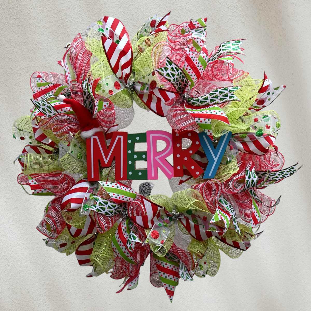 Whimsical Merry Christmas wreath with adjustable Santa hat and red, white and green ribbons