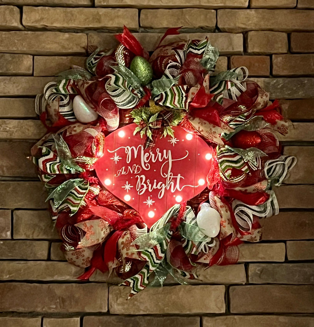 Merry and Bright Christmas wreath glowing in a darkened room