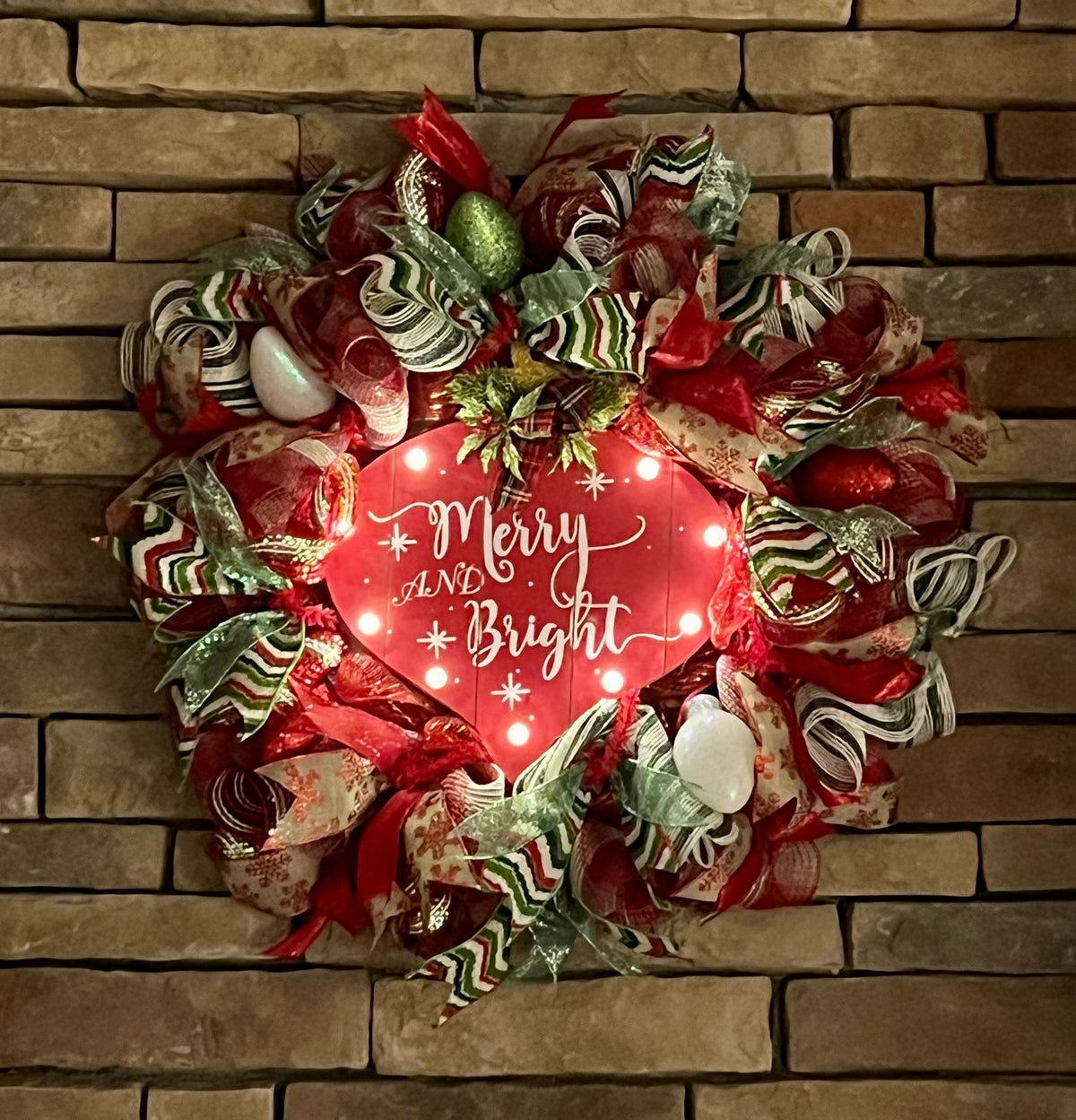 Merry and Bright Christmas wreath glowing in a darkened room