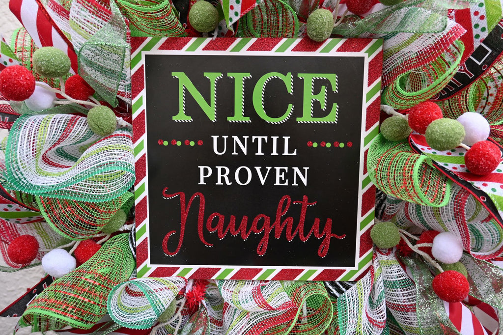 Close-up of the black Nice Until Proven Naughty sign on the Christmas wreath