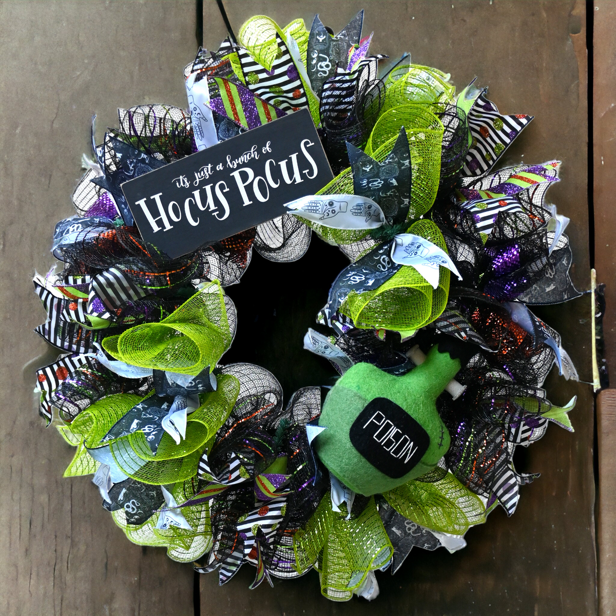 Poison Bottle Halloween wreath with Hocus Pocus sign, black, lime green, purple and orange ribbons for witchy front door decor.