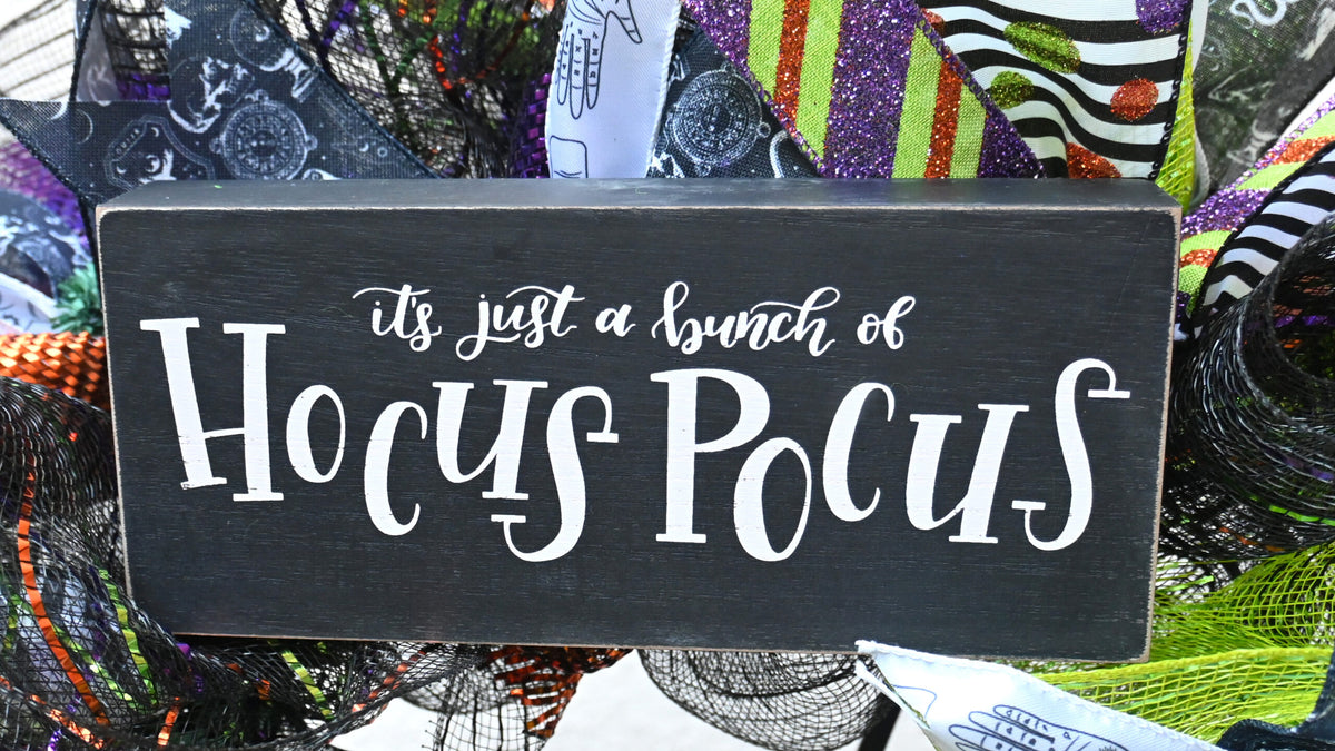 Close-up of It’s just a bunch of Hocus Pocus sign on a poison bottle Halloween wreath with purple, green, orange and black accents.