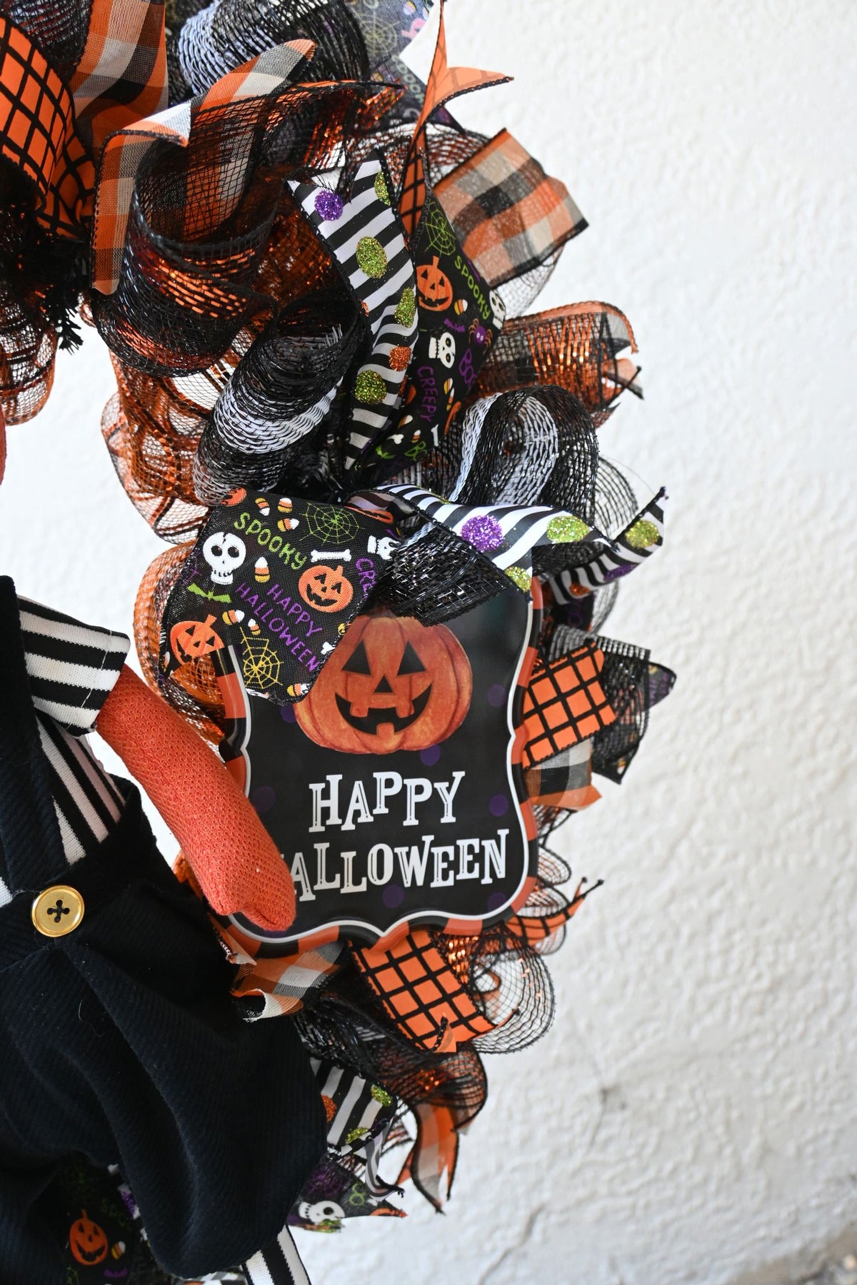 Close-up of Happy Halloween sign on a Pumpkinhead wreath with festive orange, black and white decor.