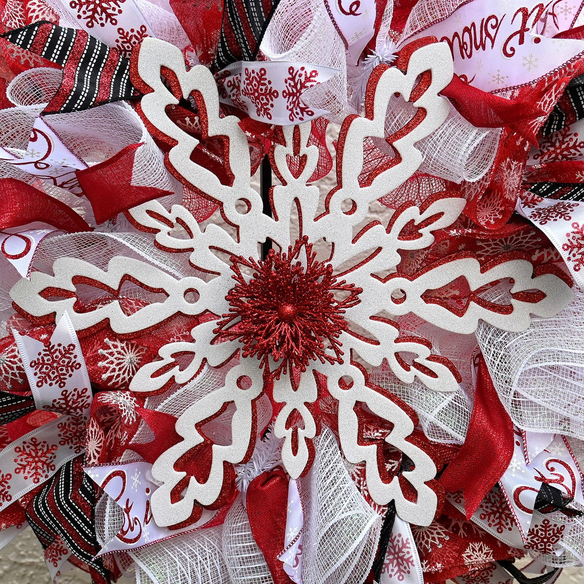 Close-up of red and white Winter Snowflake Wreath showing layered ribbons, snowflake accents, and winter door decor details.