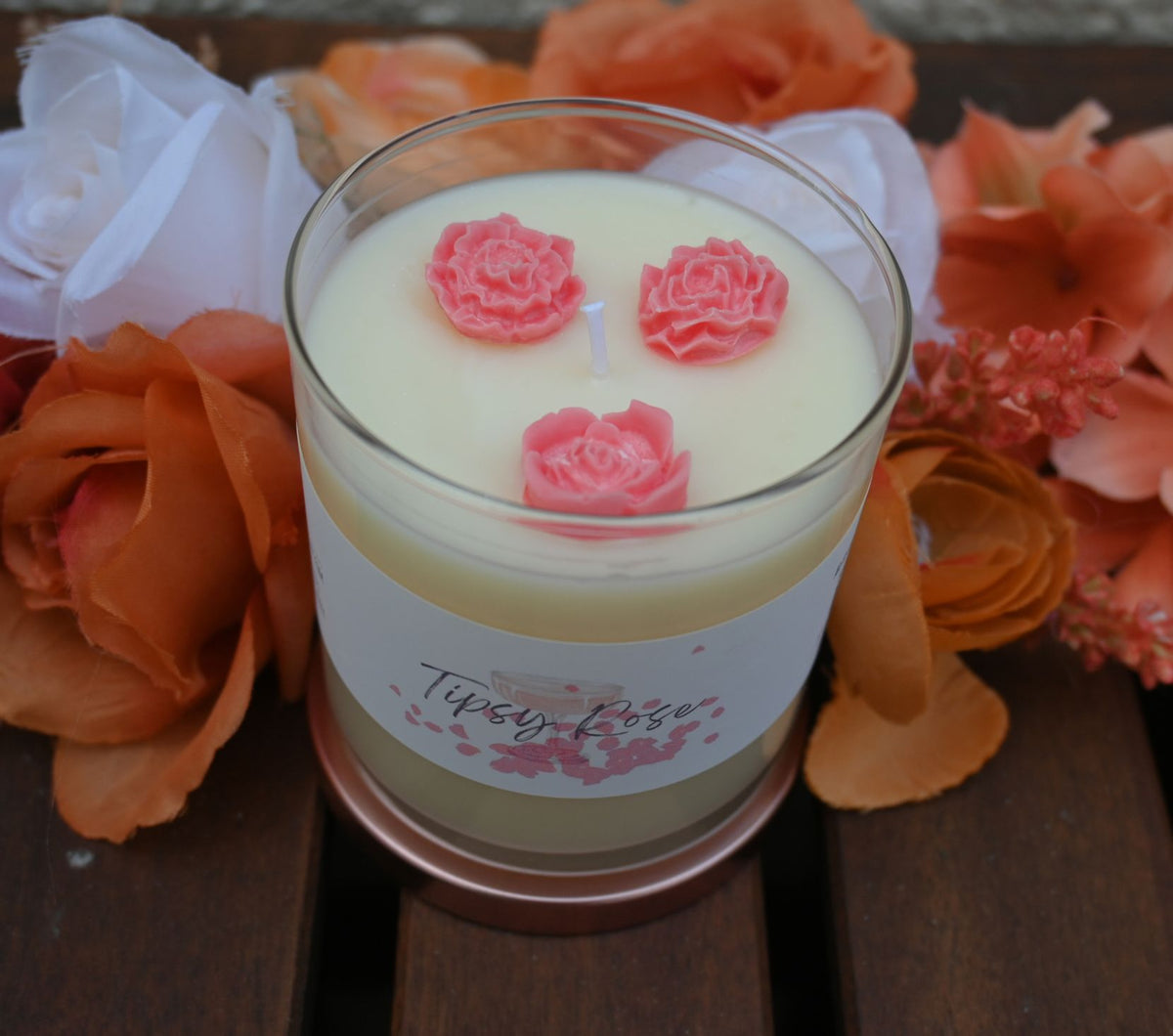 Top view of Tipsy Rose candle showing three pink rose accents on pale wax around the wick