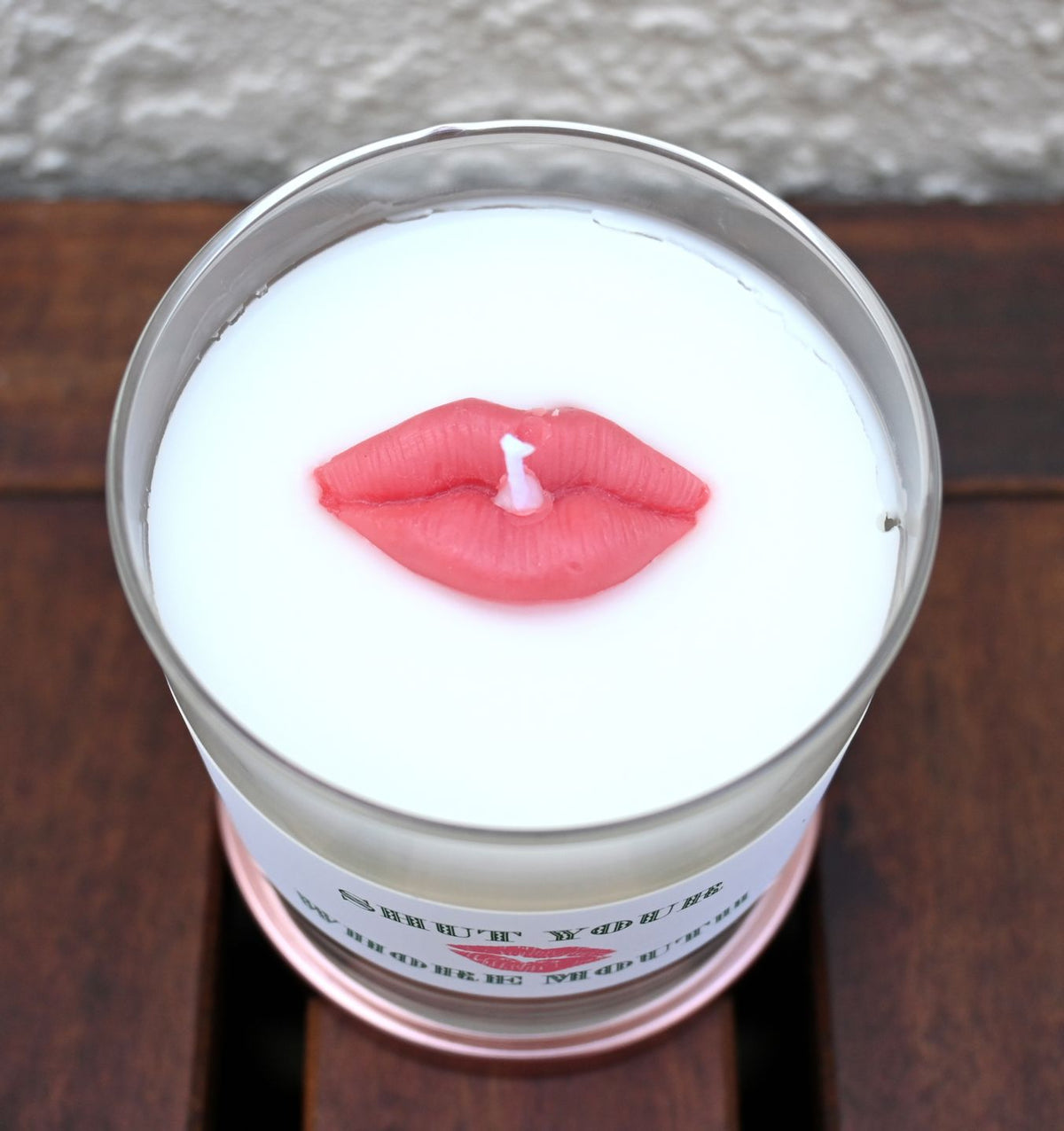 Top view of mint and basil candle with red lips accent surrounding the wick
